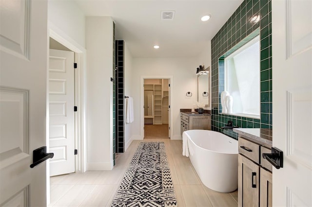 bathroom with a bath, vanity, and tile patterned flooring