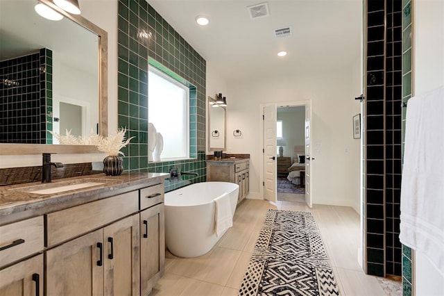 bathroom with a bathtub, tile patterned floors, vanity, and tile walls