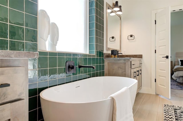 bathroom with a tub to relax in, vanity, tile patterned flooring, and tile walls