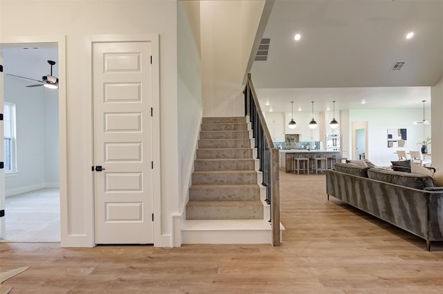 staircase featuring ceiling fan and wood-type flooring