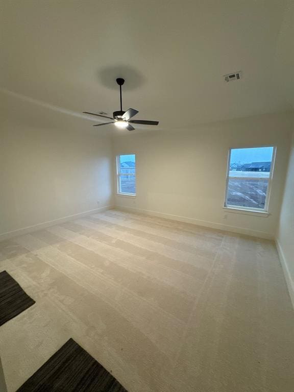 spare room with ceiling fan and light colored carpet