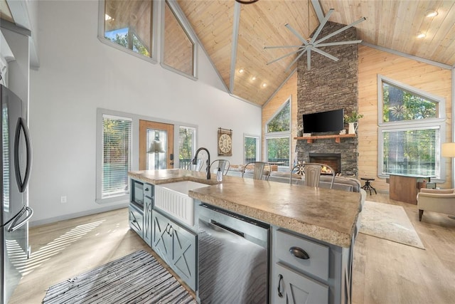 kitchen featuring appliances with stainless steel finishes, wood ceiling, wooden walls, and high vaulted ceiling