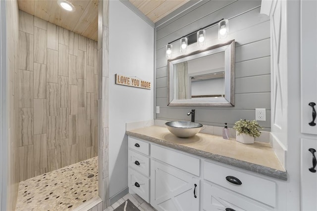 bathroom with a shower, vanity, wood walls, and wood ceiling