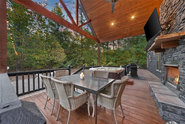 deck featuring a hot tub and an outdoor stone fireplace