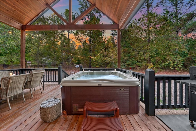 deck at dusk featuring a hot tub