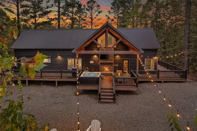 back house at dusk with a deck and an outdoor stone fireplace