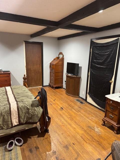 bedroom featuring beamed ceiling and light wood finished floors