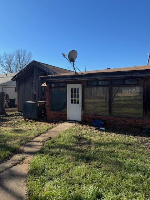 rear view of house featuring cooling unit and a yard