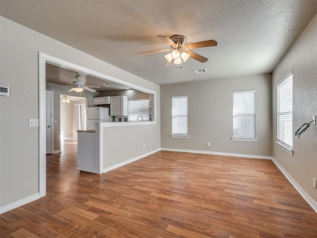 unfurnished living room with ceiling fan, hardwood / wood-style flooring, and a textured ceiling