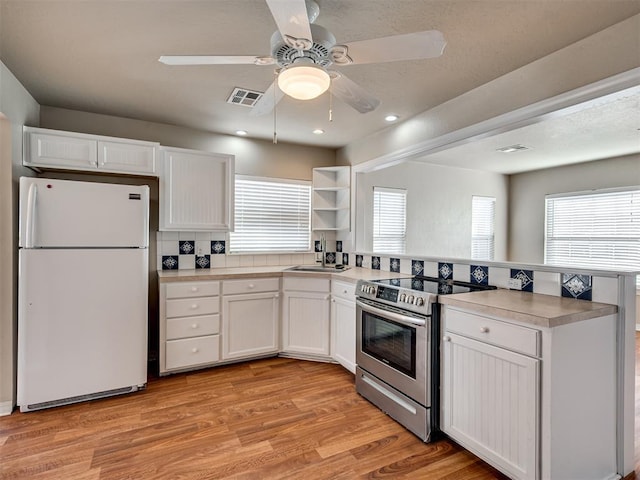 kitchen with sink, white cabinetry, stainless steel electric range, light hardwood / wood-style flooring, and white fridge