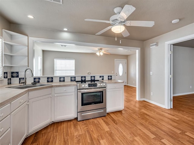 kitchen with sink, white cabinets, stainless steel range with electric stovetop, ceiling fan, and light hardwood / wood-style flooring