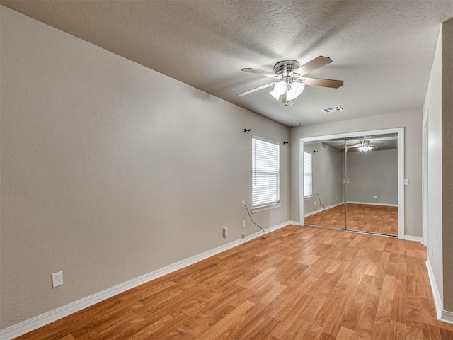 unfurnished bedroom featuring light wood-type flooring, a textured ceiling, ceiling fan, and a closet