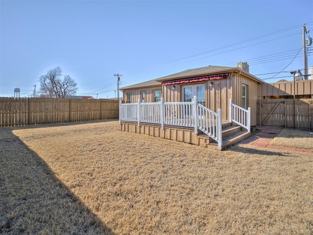 rear view of property with a wooden deck and a lawn