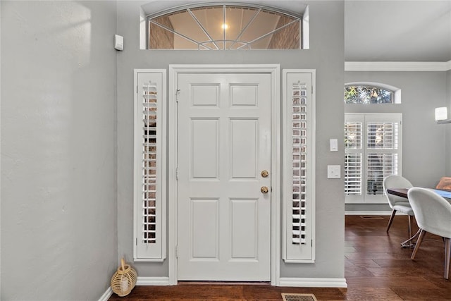 foyer with ornamental molding and dark hardwood / wood-style flooring