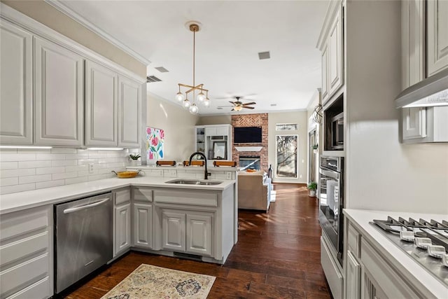 kitchen featuring sink, stainless steel appliances, ornamental molding, decorative light fixtures, and kitchen peninsula