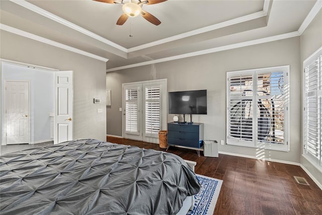 bedroom with crown molding, ceiling fan, a raised ceiling, and dark wood-type flooring