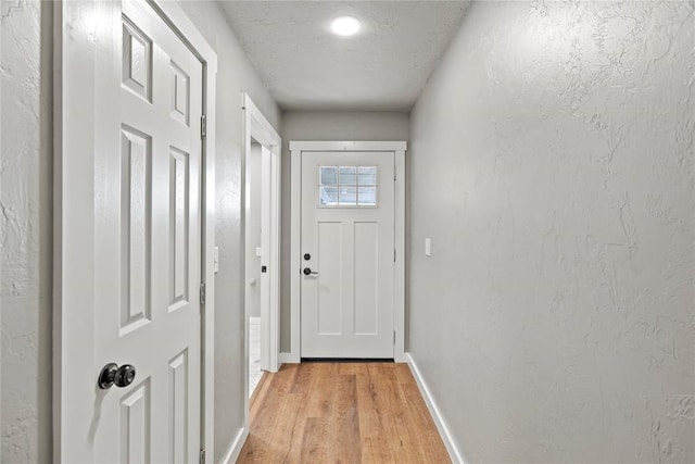 doorway with light hardwood / wood-style flooring and a textured ceiling