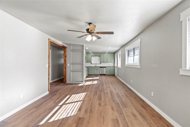 unfurnished living room with ceiling fan, sink, and light wood-type flooring