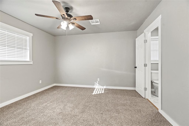 carpeted empty room with a wealth of natural light and ceiling fan