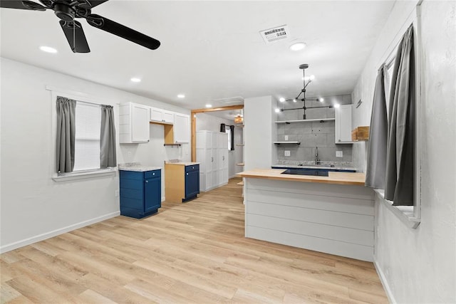 kitchen featuring butcher block counters, white cabinetry, blue cabinets, sink, and kitchen peninsula