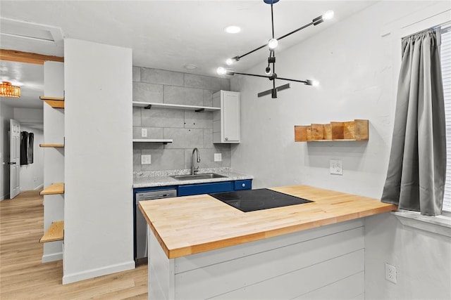 kitchen featuring black electric stovetop, dishwasher, wooden counters, sink, and white cabinets