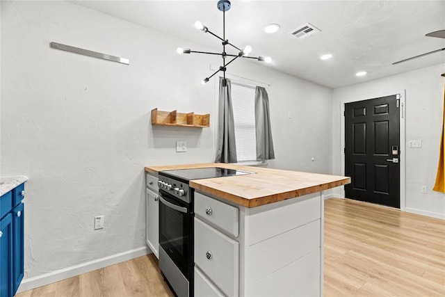 kitchen with pendant lighting, wooden counters, white cabinetry, electric range, and light hardwood / wood-style floors