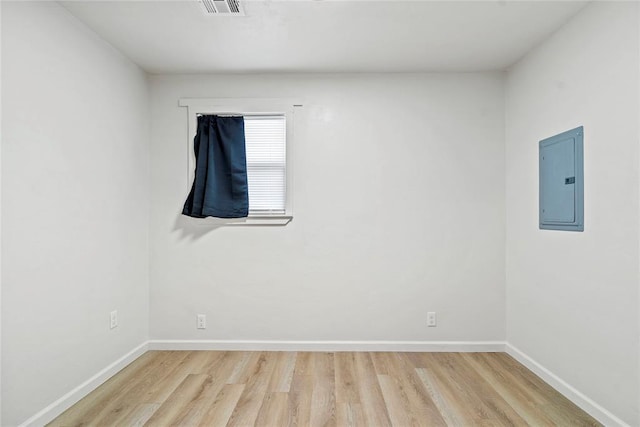 spare room with electric panel and hardwood / wood-style floors