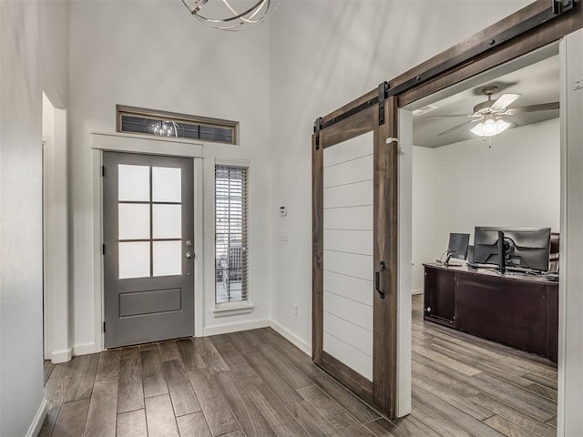 entryway featuring ceiling fan, hardwood / wood-style floors, a towering ceiling, and a barn door