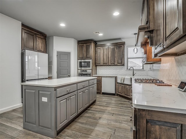 kitchen featuring decorative backsplash, dark brown cabinetry, stainless steel appliances, and a kitchen island