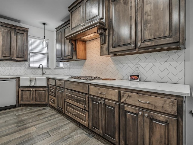 kitchen with stainless steel gas stovetop, dark hardwood / wood-style floors, sink, hanging light fixtures, and dishwashing machine