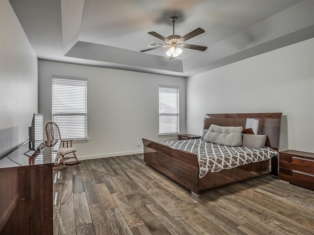 bedroom with ceiling fan, a tray ceiling, and hardwood / wood-style floors