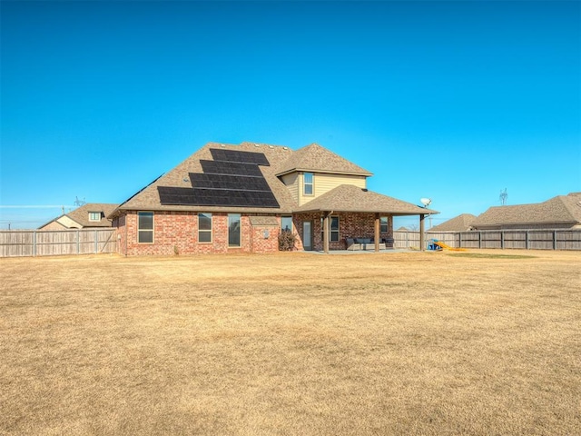 back of property featuring a yard and solar panels