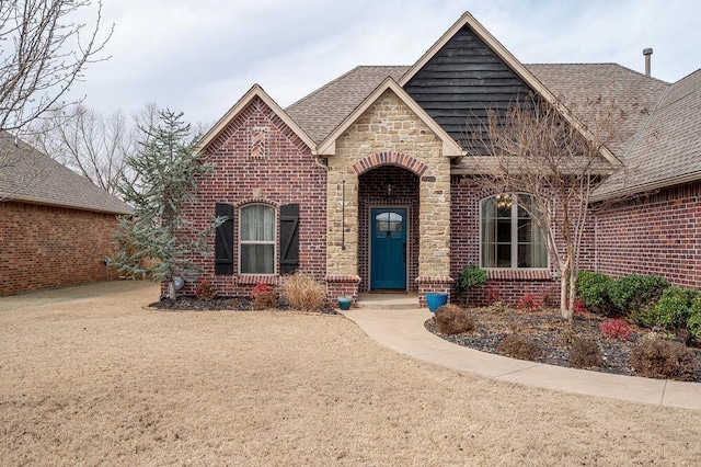 view of front of house featuring brick siding, stone siding, and roof with shingles