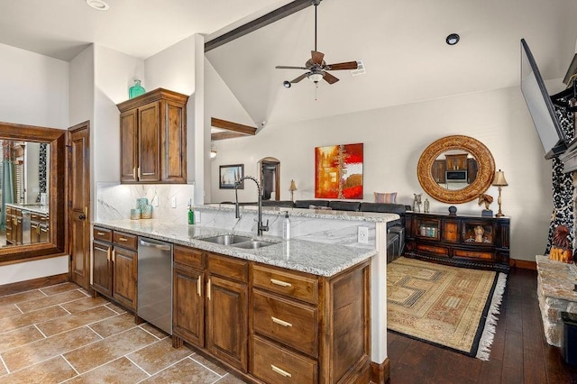 kitchen featuring light stone countertops, lofted ceiling, decorative backsplash, a peninsula, and a sink