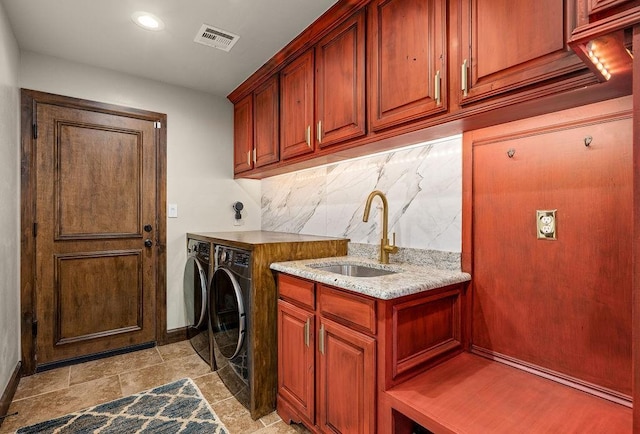 washroom with baseboards, visible vents, cabinet space, a sink, and independent washer and dryer