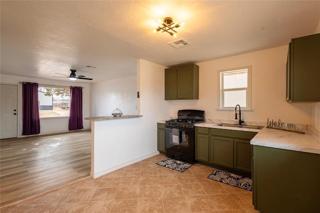 kitchen with black gas range oven, green cabinetry, a textured ceiling, and sink