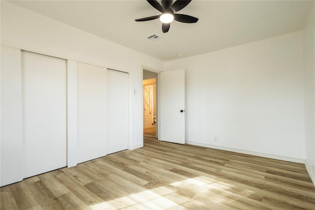 unfurnished bedroom featuring ceiling fan, multiple closets, and light wood-type flooring