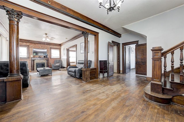 living room with brick wall, ceiling fan with notable chandelier, ornamental molding, and hardwood / wood-style floors