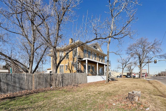 view of side of home featuring a yard and a balcony