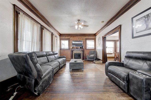 living room featuring a textured ceiling, brick wall, dark hardwood / wood-style flooring, ceiling fan, and a tile fireplace