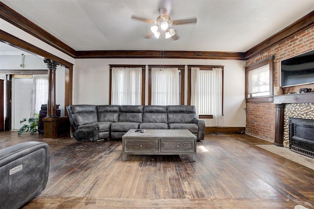 living room with a textured ceiling, ceiling fan, dark hardwood / wood-style flooring, and a brick fireplace