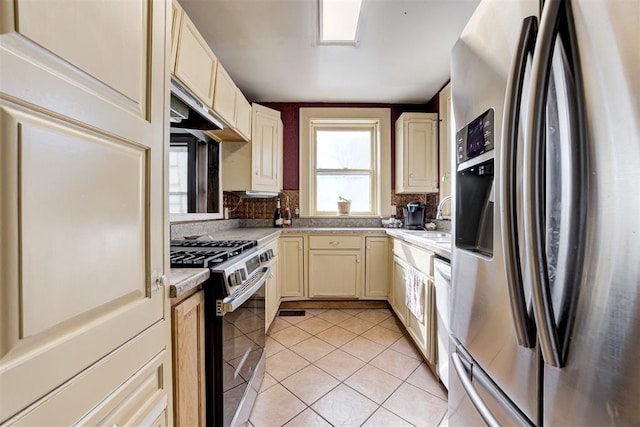 kitchen with light tile patterned floors, stainless steel appliances, cream cabinetry, and sink