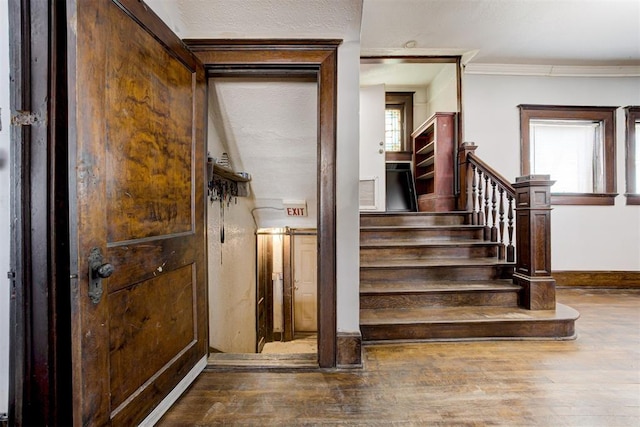 stairway with hardwood / wood-style floors and ornamental molding