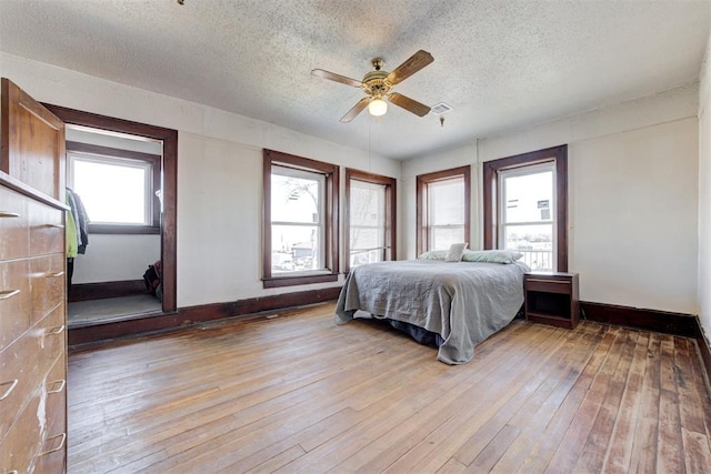 bedroom with a textured ceiling, ceiling fan, and light hardwood / wood-style floors