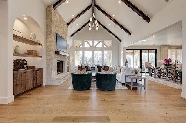 living room featuring beamed ceiling, light hardwood / wood-style flooring, a stone fireplace, and high vaulted ceiling