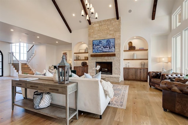 living room featuring a stone fireplace, built in features, high vaulted ceiling, light hardwood / wood-style flooring, and beam ceiling