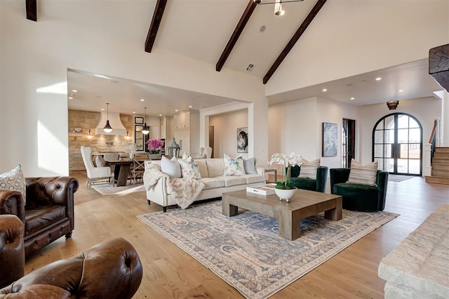 living room featuring light wood-type flooring, high vaulted ceiling, and beamed ceiling