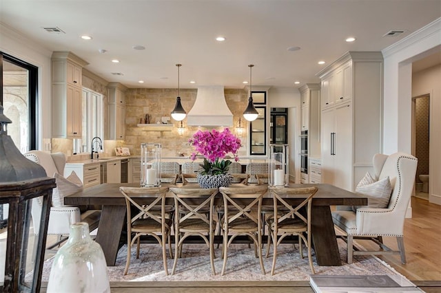 dining space with crown molding, light hardwood / wood-style floors, and sink