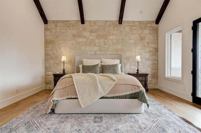 bedroom featuring wood-type flooring and vaulted ceiling with beams