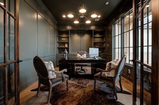 office space featuring french doors, crown molding, and light hardwood / wood-style flooring